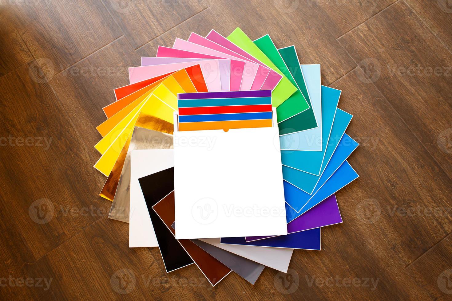 gedraaide stapel kleurrijke 12x12 vellen zelfklevend papier, doos geïsoleerd foto