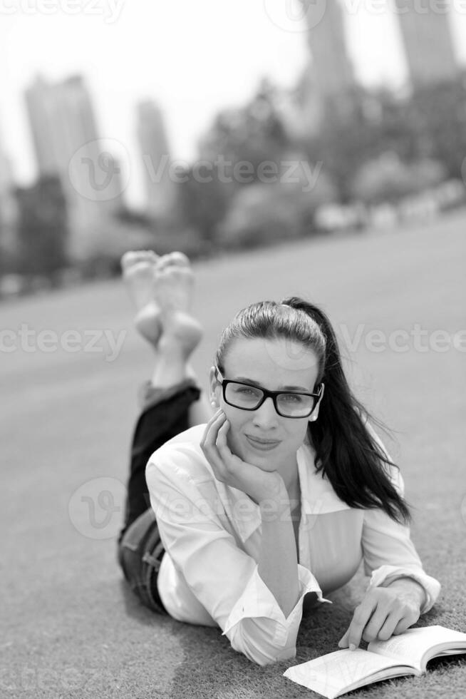 jonge vrouw die een boek in het park leest foto