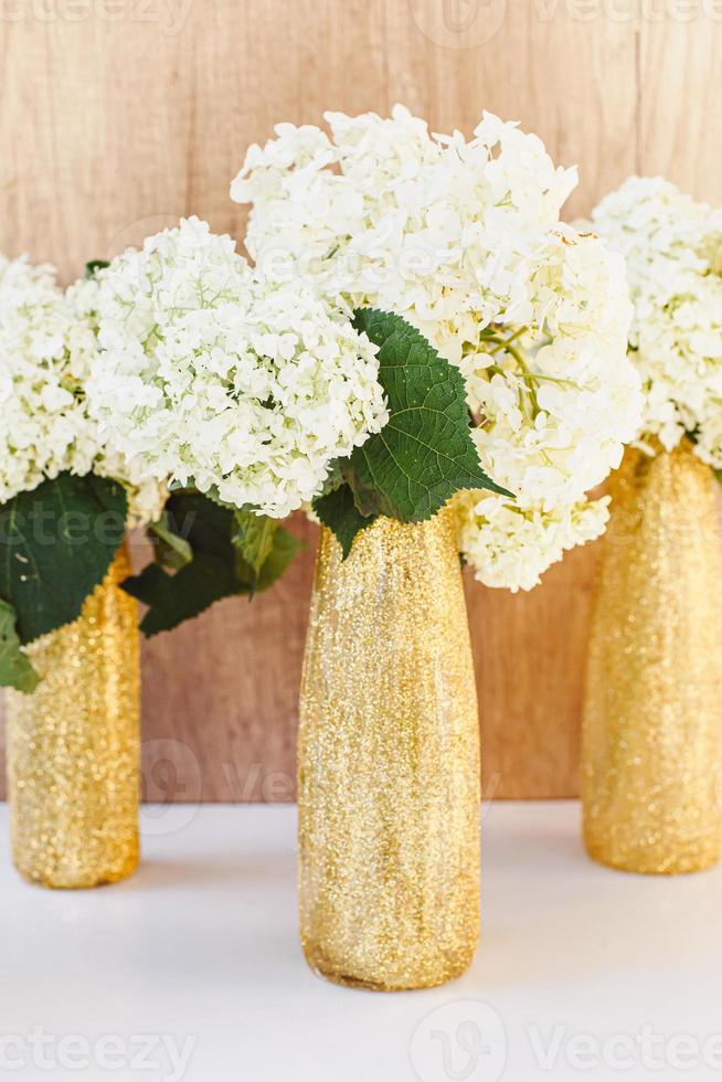 gouden glitterflessen met hortensia bloemen. gouden vazen foto