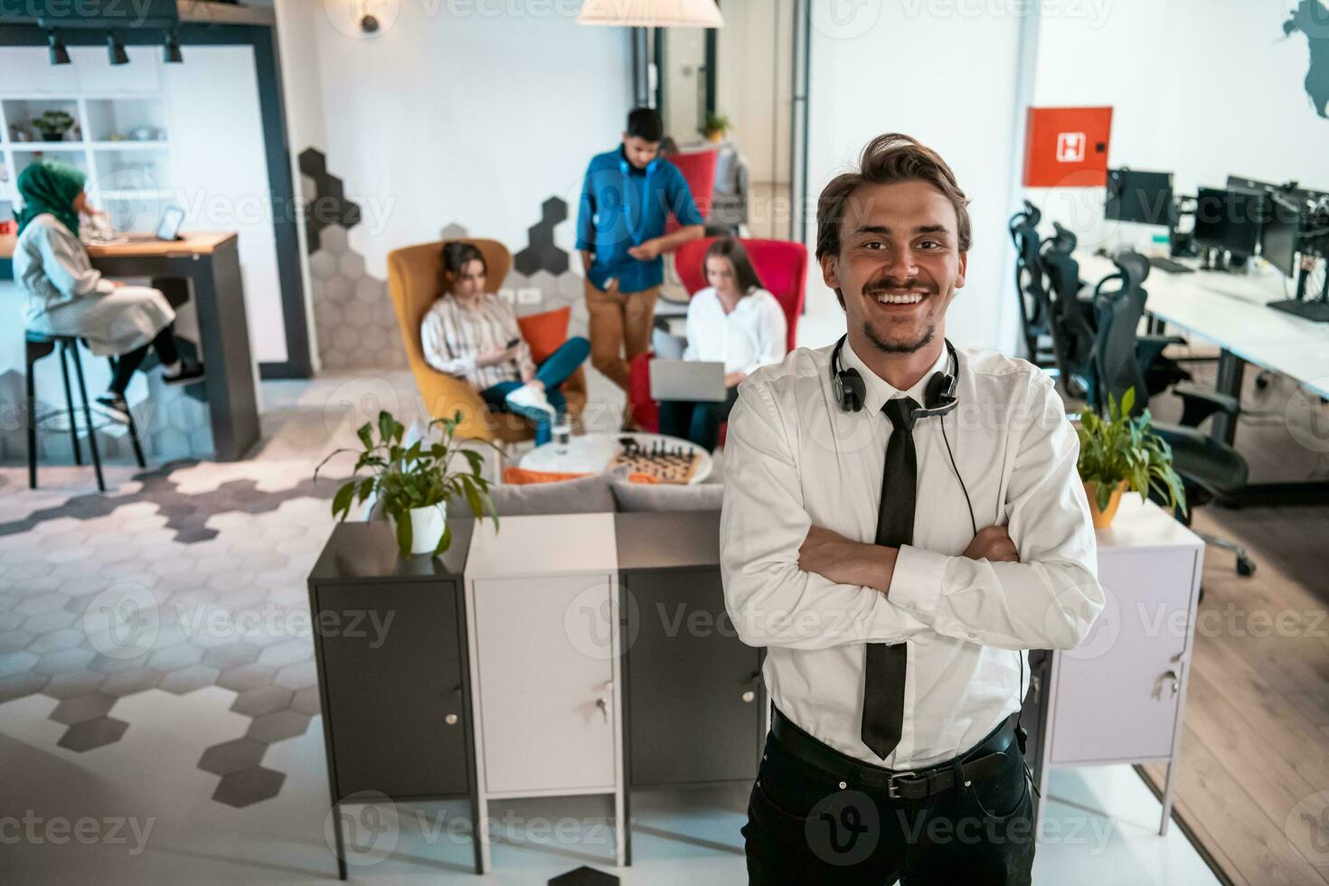 portret van geslaagd zakenman ondernemer met hoofdtelefoons in de omgeving van zijn nek en collega's in de achtergrond Bij bezig opstarten kantoor foto