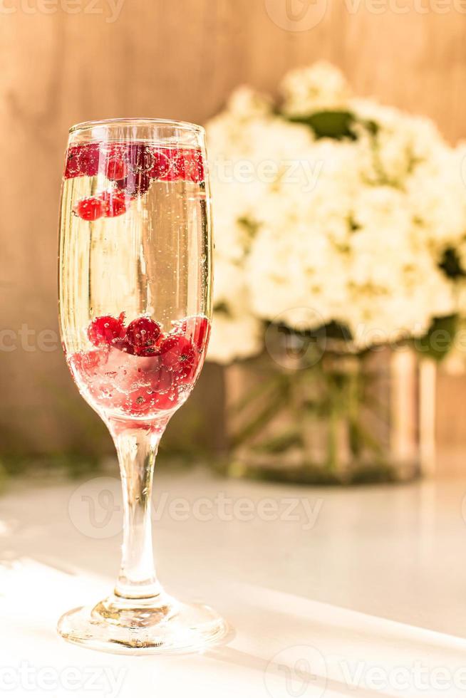 Mousserende wijn in glas met rode aalbessen foto