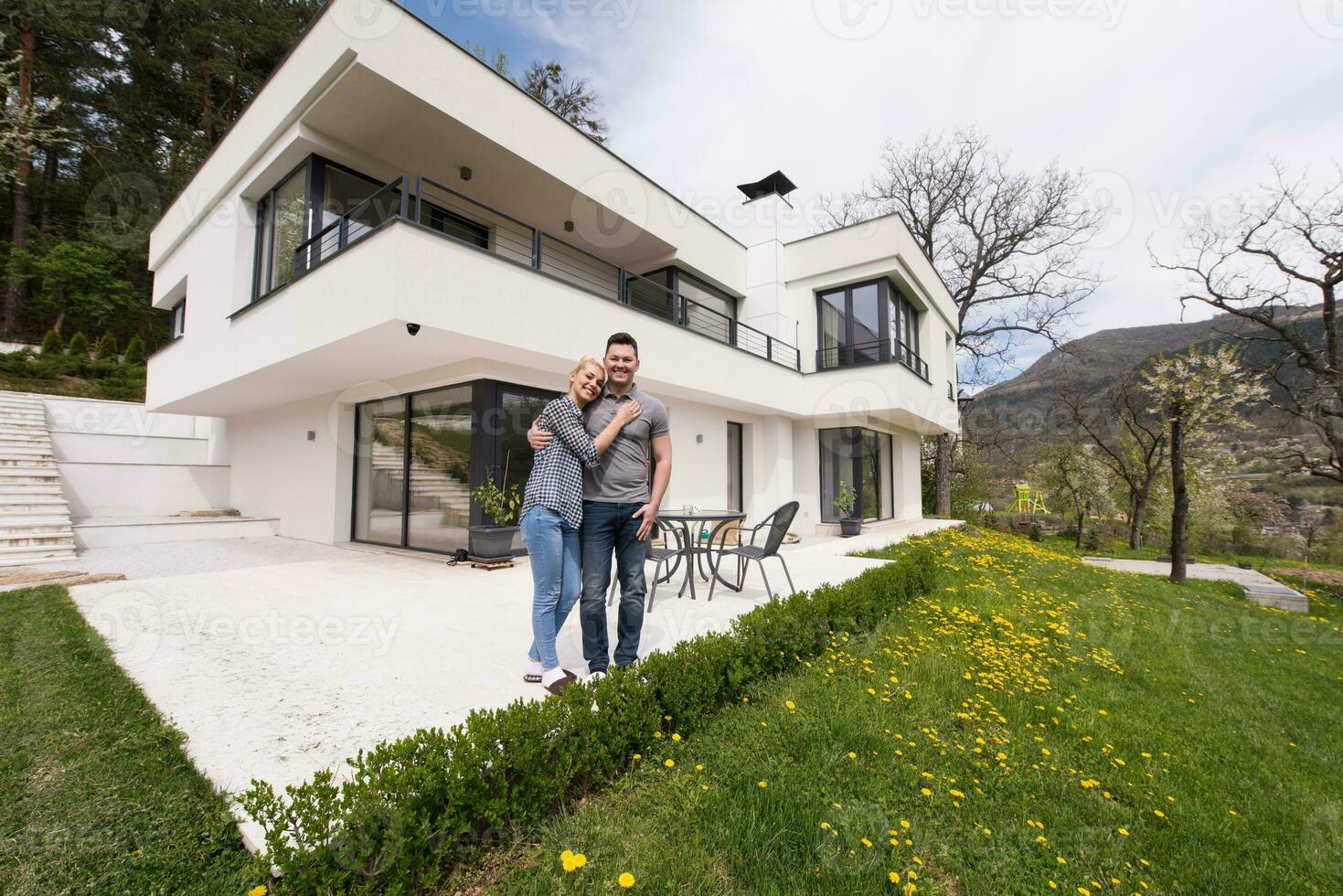 paar knuffelen in voorkant van nieuw luxe huis foto