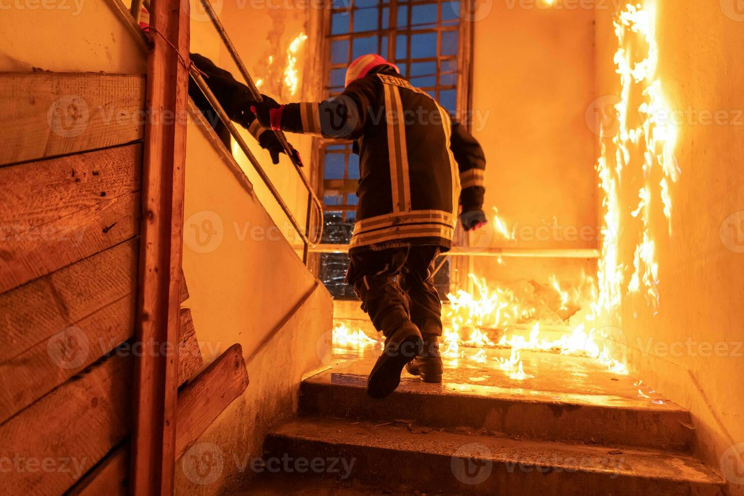 dapper brandweerman gaan boven naar opslaan en redden mensen in een brandend gebouw. Open brand en vlam. foto