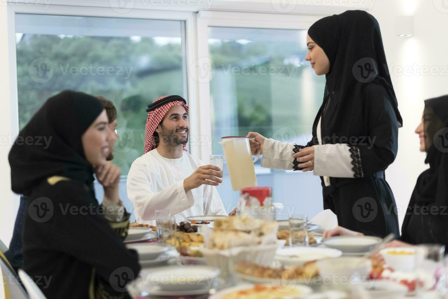 eid mubarak moslim familie hebben iftar avondeten drinken water naar breken feest. aan het eten traditioneel voedsel gedurende Ramadan feesten maand Bij huis. de Islamitisch halal aan het eten en drinken Bij modern western isla foto