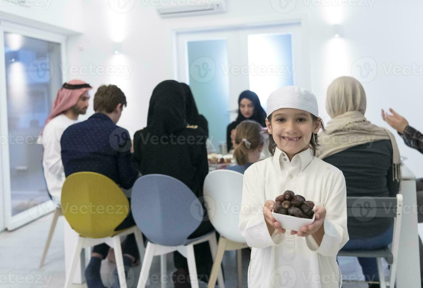 eid mubarak moslim familie hebben iftar avondeten weinig jongen Holding een bord vol van zoet datums naar breken feest. aan het eten traditioneel voedsel gedurende Ramadan feesten maand Bij huis. de Islamitisch halal aan het eten foto