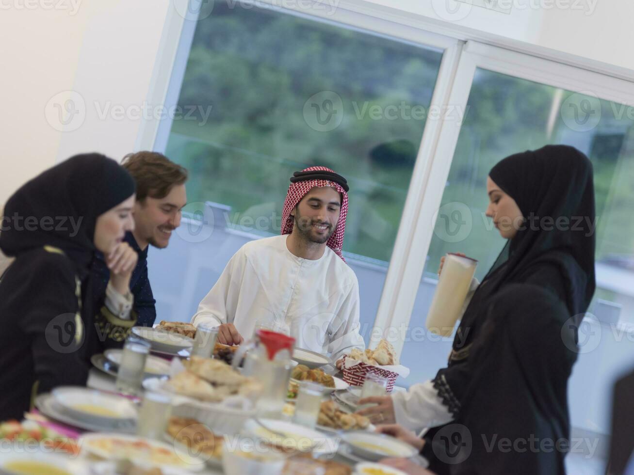 eid mubarak moslim familie hebben iftar avondeten drinken water naar breken feest. aan het eten traditioneel voedsel gedurende Ramadan feesten maand Bij huis. de Islamitisch halal aan het eten en drinken Bij modern western isla foto