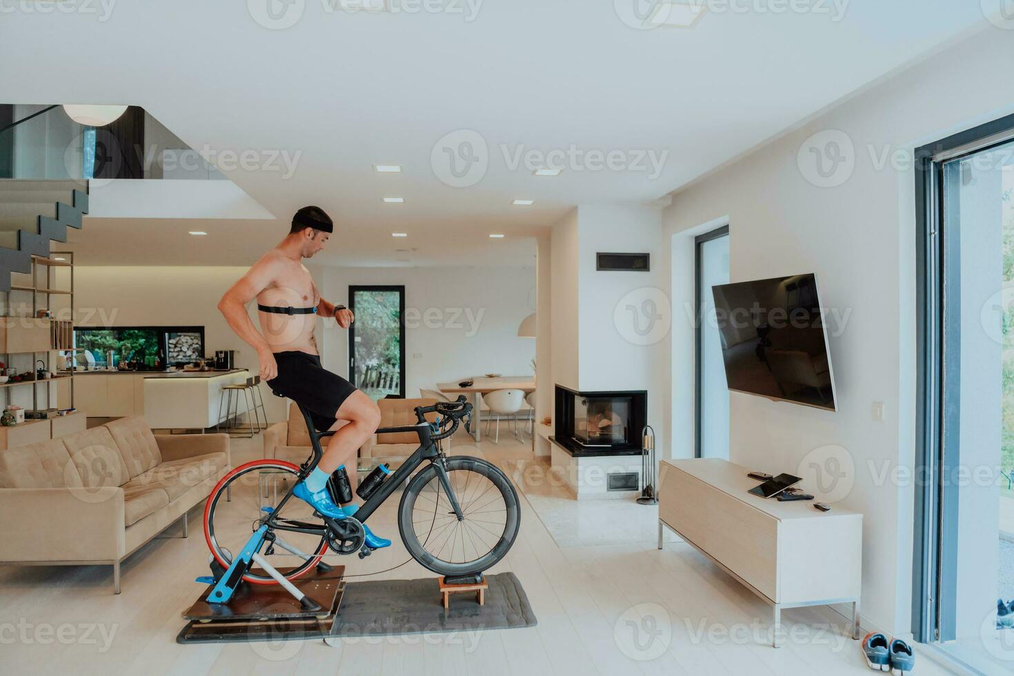 een Mens rijden een triatlon fiets Aan een machine simulatie in een modern leven kamer. opleiding gedurende pandemisch conditie. foto