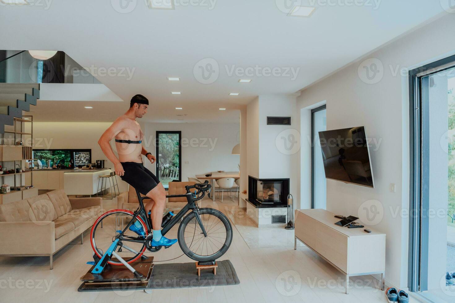 een Mens rijden een triatlon fiets Aan een machine simulatie in een modern leven kamer. opleiding gedurende pandemisch conditie. foto