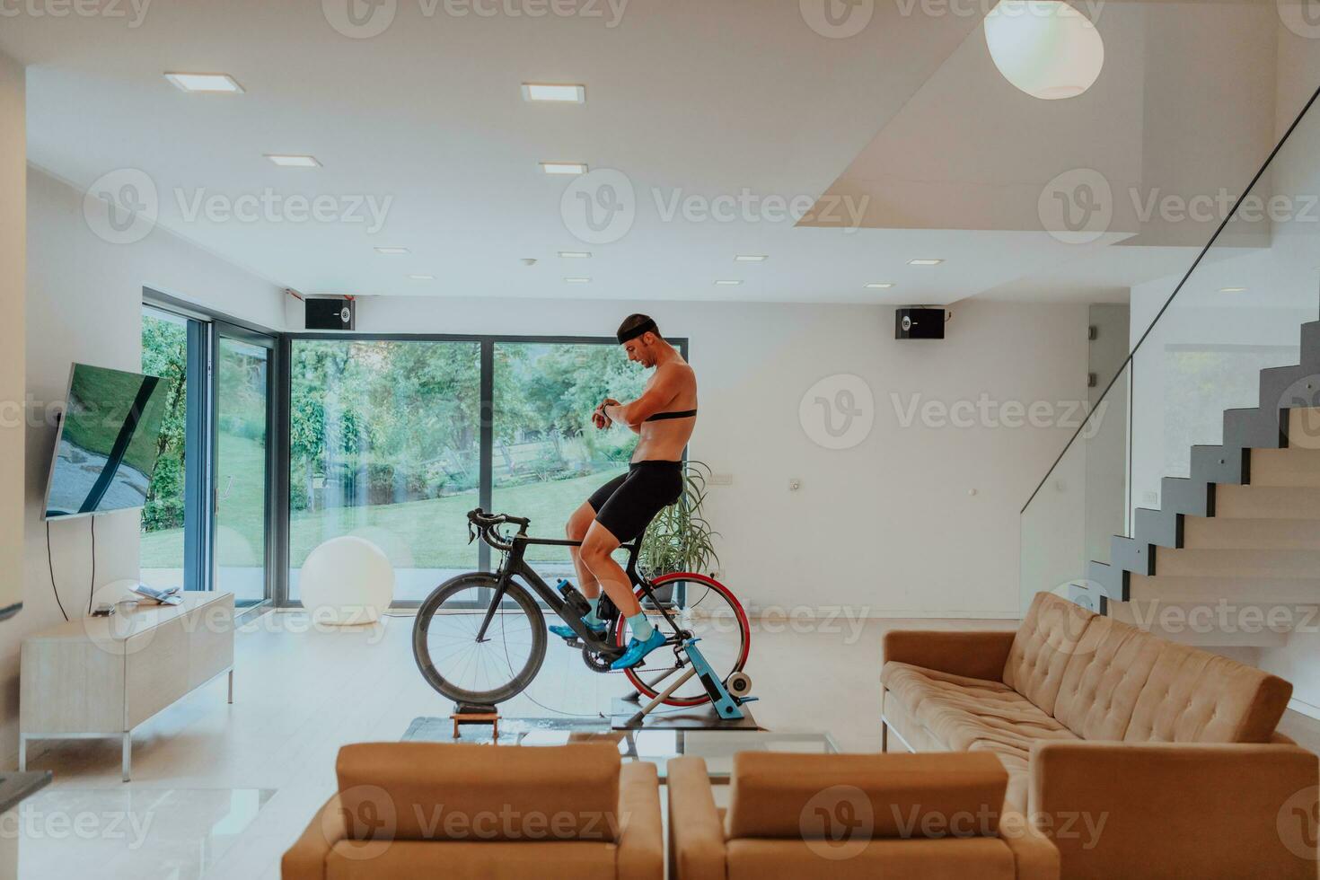 een Mens rijden een triatlon fiets Aan een machine simulatie in een modern leven kamer. opleiding gedurende pandemisch conditie. foto