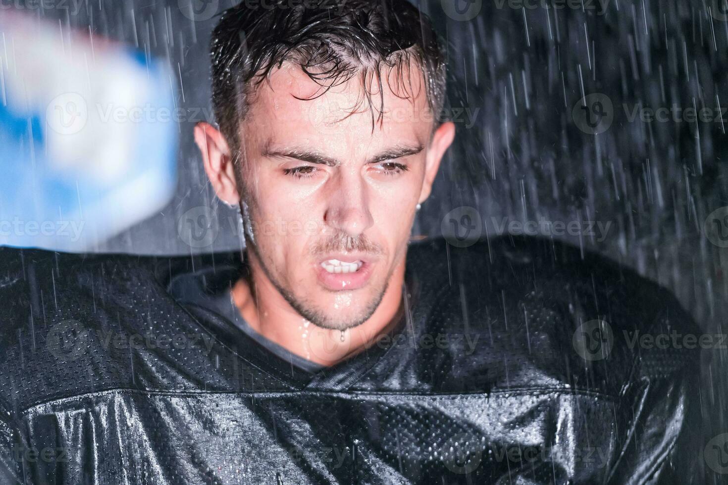 Amerikaans Amerikaans voetbal veld- eenzaam atleet krijger staand Aan een veld- houdt zijn helm en klaar naar Speel. speler voorbereidingen treffen naar rennen, aanval en partituur touchdown. regenachtig nacht met dramatisch mist, blauw licht foto