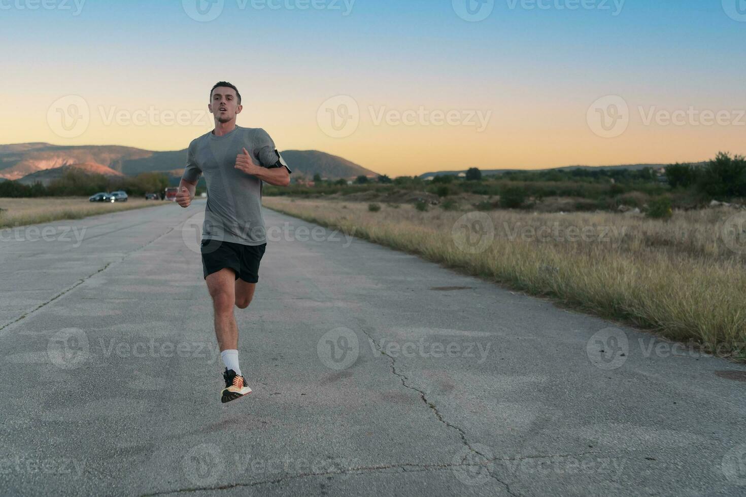 aantrekkelijk fit Mens rennen snel langs platteland weg Bij zonsondergang licht, aan het doen jogging training buitenshuis foto