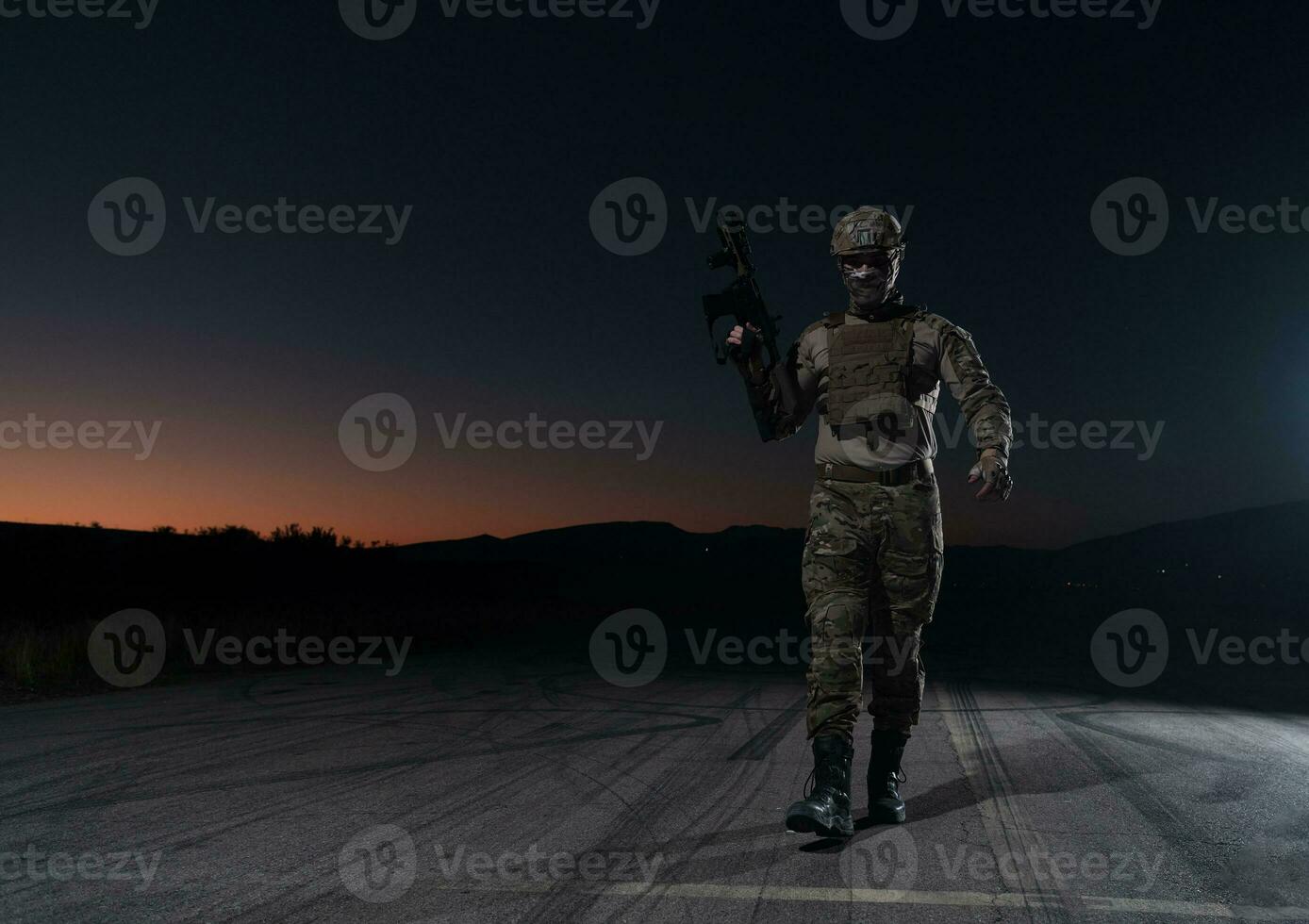 leger soldaat in gevecht uniformen met een aanval geweer, bord vervoerder en gevecht helm gaan Aan een gevaarlijk missie Aan een regenachtig nacht. foto