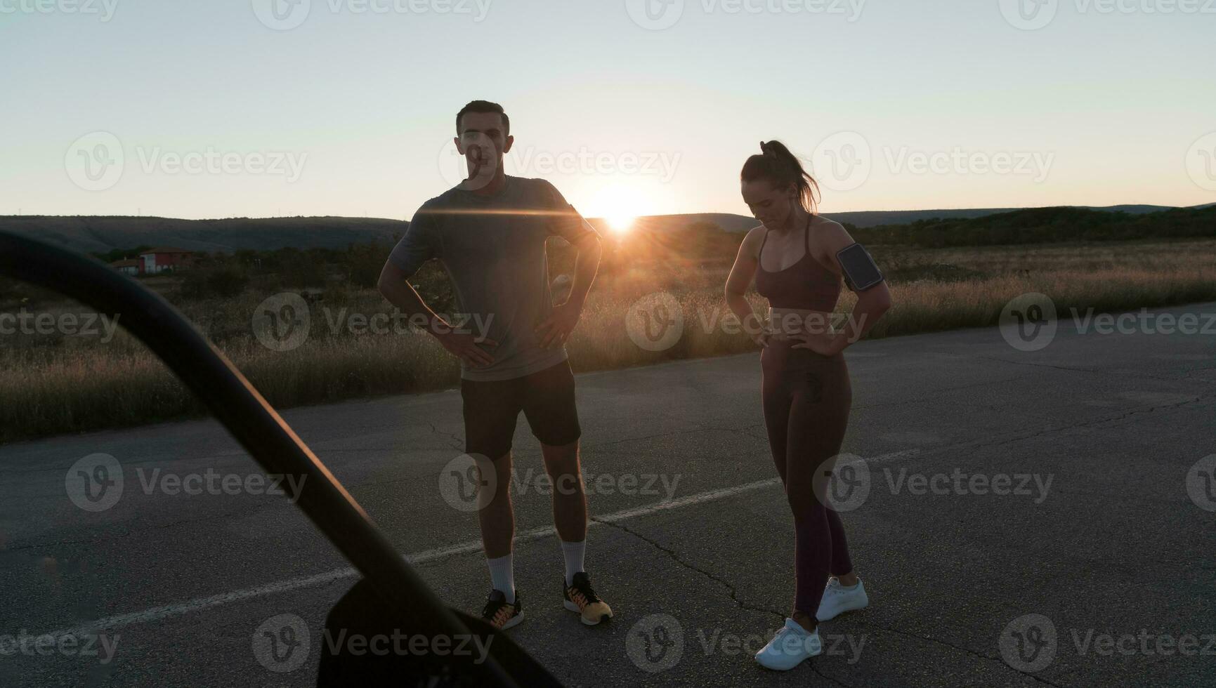 gezond jong paar jogging in de stad straten in de vroeg ochtend- met een mooi zonsopkomst in de achtergrond. foto