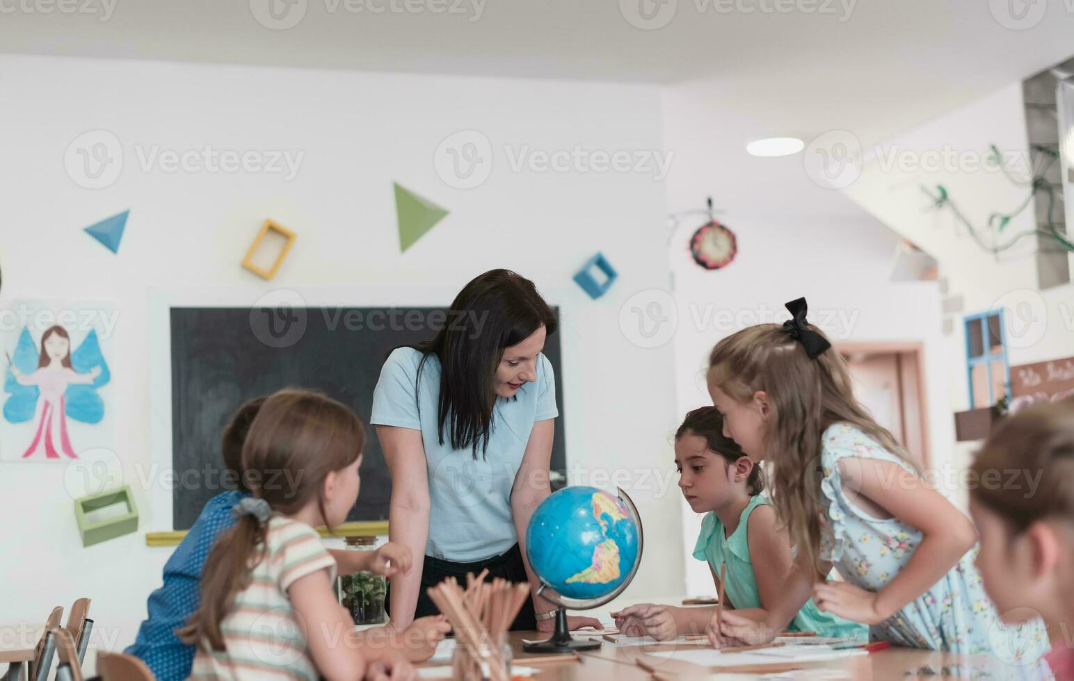 vrouw leraar met kinderen in aardrijkskunde klasse op zoek Bij wereldbol. kant visie van groep van verschillend gelukkig school- kinderen met wereldbol in klas Bij school. foto