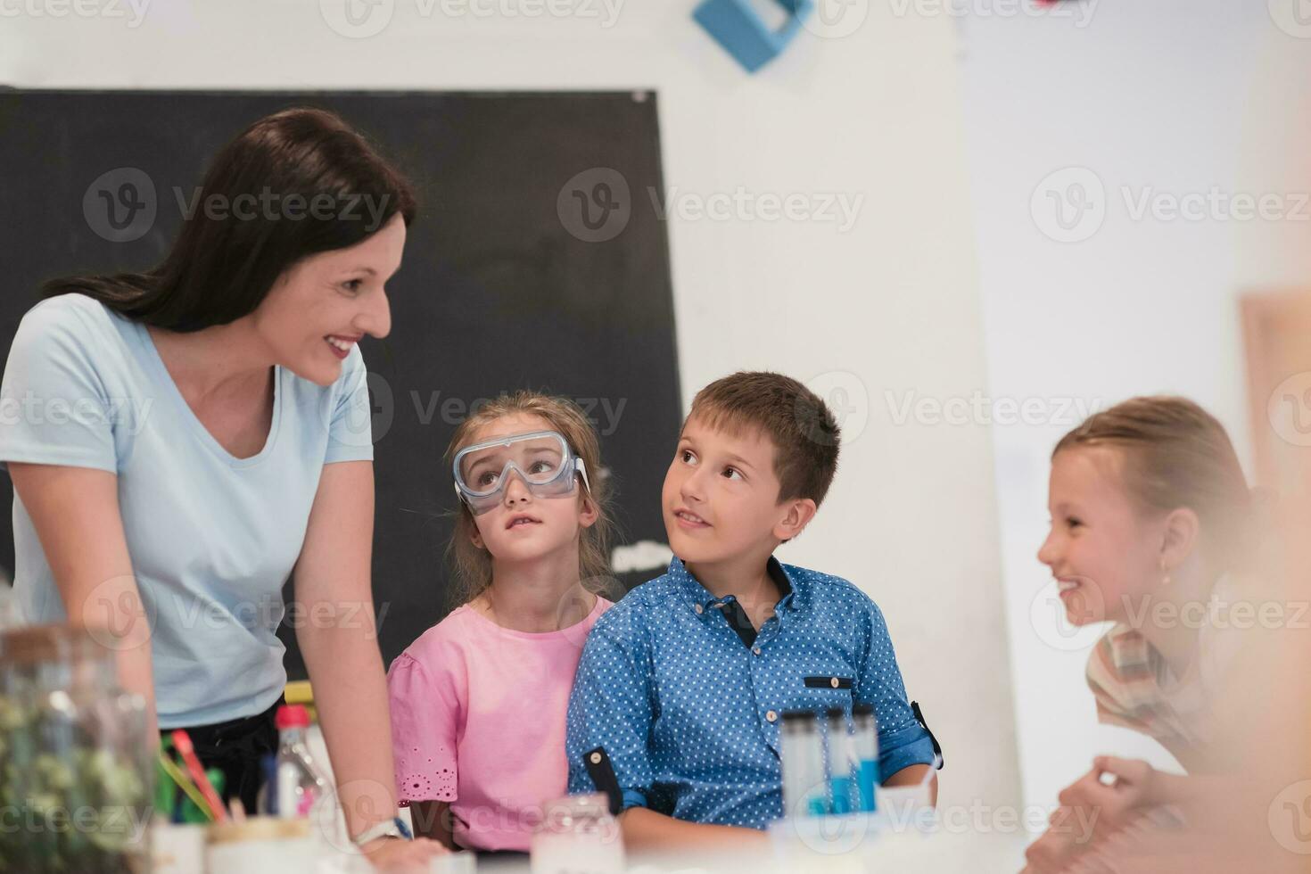 elementair school- wetenschap klas enthousiast leraar legt uit chemie naar verschillend groep van kinderen, weinig jongen mengsels Chemicaliën in bekers. kinderen leren met interesseren foto