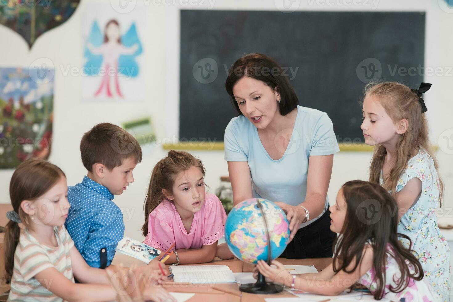 vrouw leraar met kinderen in aardrijkskunde klasse op zoek Bij wereldbol. kant visie van groep van verschillend gelukkig school- kinderen met wereldbol in klas Bij school. foto