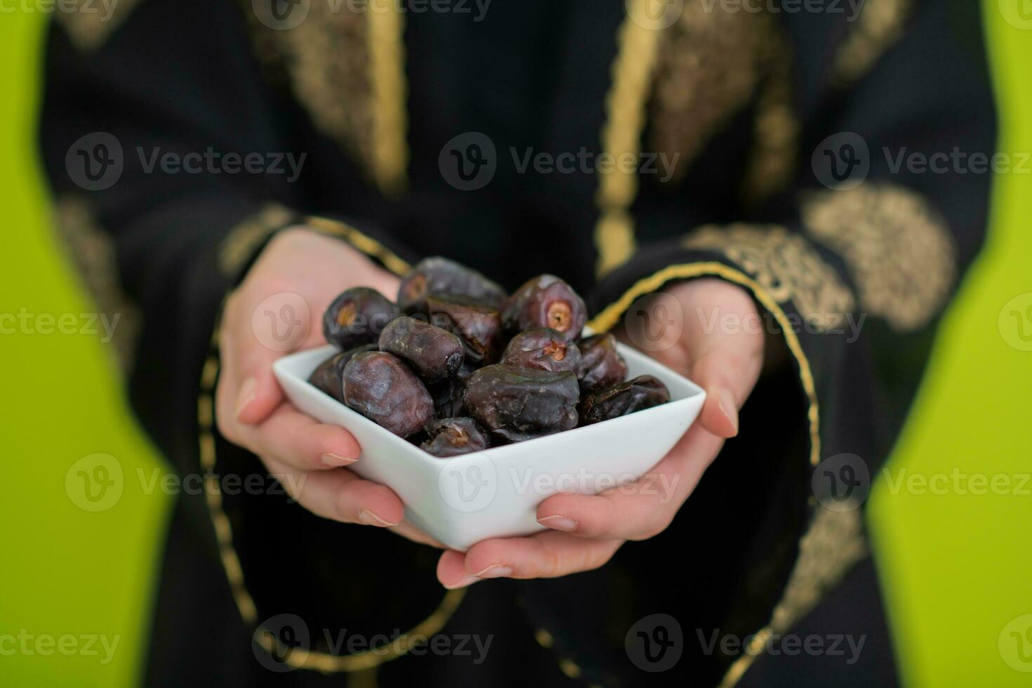 modern moslim vrouw Holding een bord vol van zoet datums Aan iftar tijd in Ramadan kareem Islamitisch gezond voedsel concept ufo groen achtergrond foto