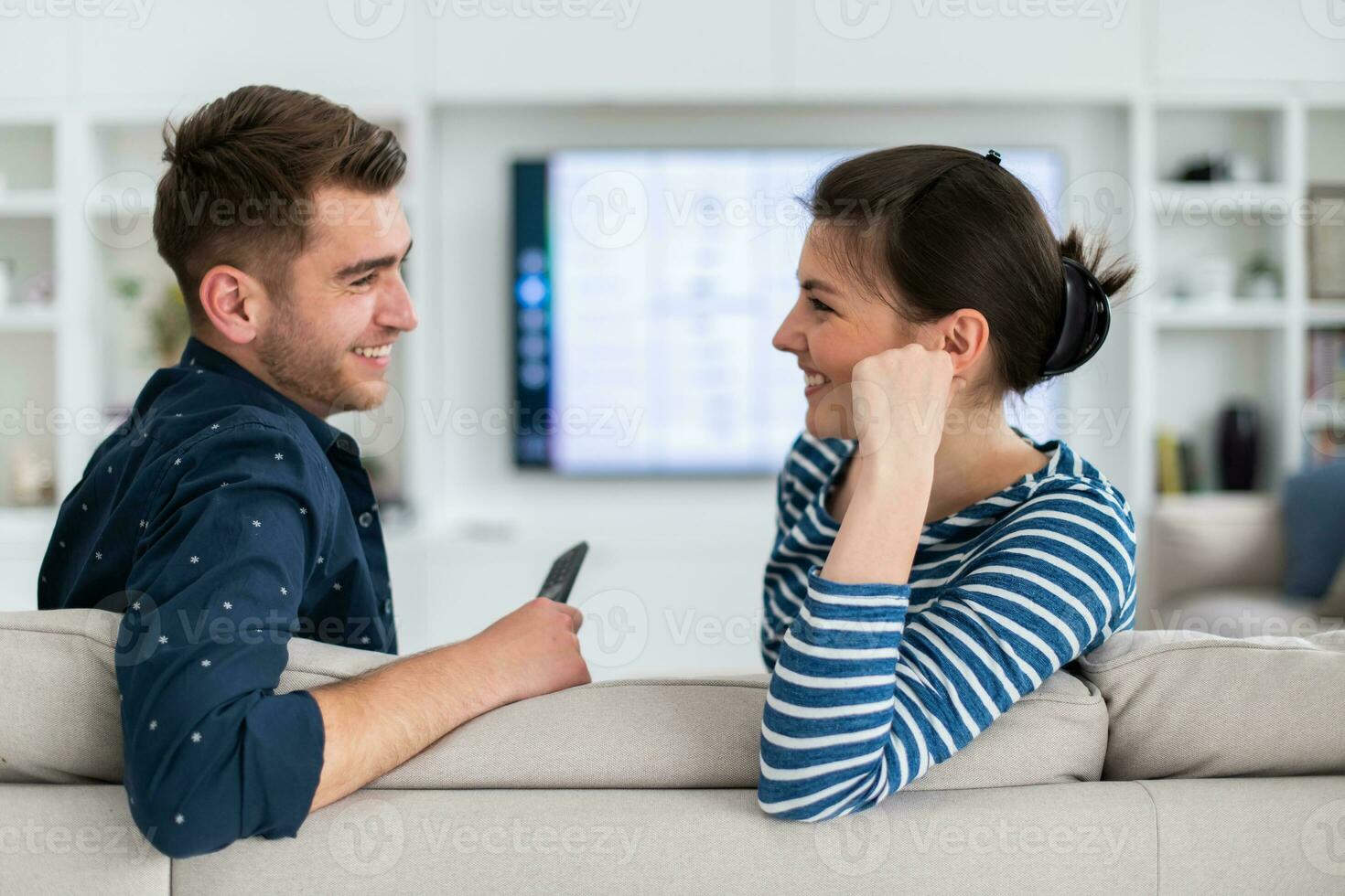 paar horloges TV samen terwijl zittend Aan een bankstel in de leven kamer. vriendin en vriendje omarmen, knuffel, praten, glimlach en kijk maar televisie streaming Diensten. huis met knus elegant interieur. foto