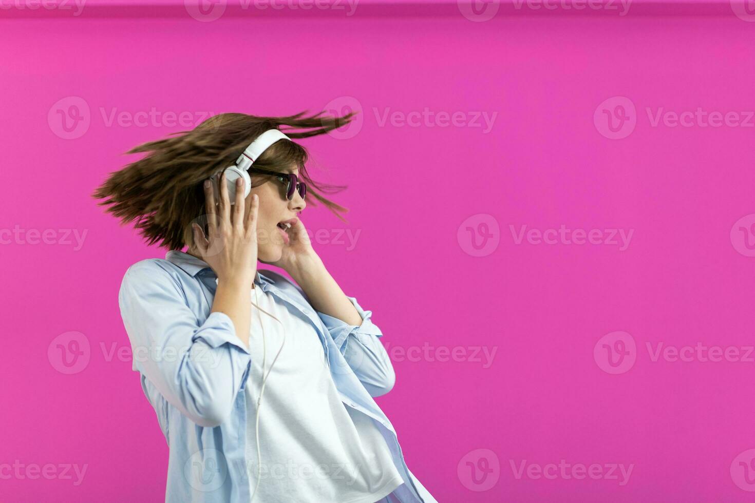 brunette dame in zwart bril dansen en luisteren muziek- isoleren Aan roze achtergrond foto