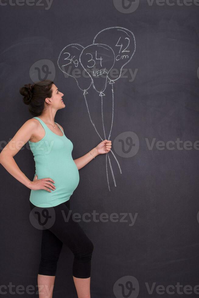portret van zwanger vrouw in voorkant van zwart schoolbord foto