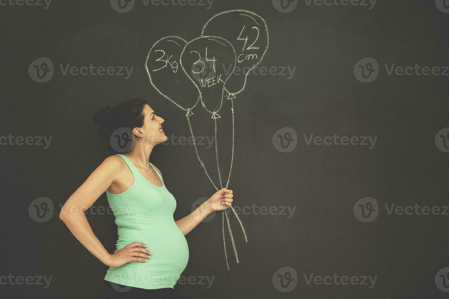 portret van zwanger vrouw in voorkant van zwart schoolbord foto