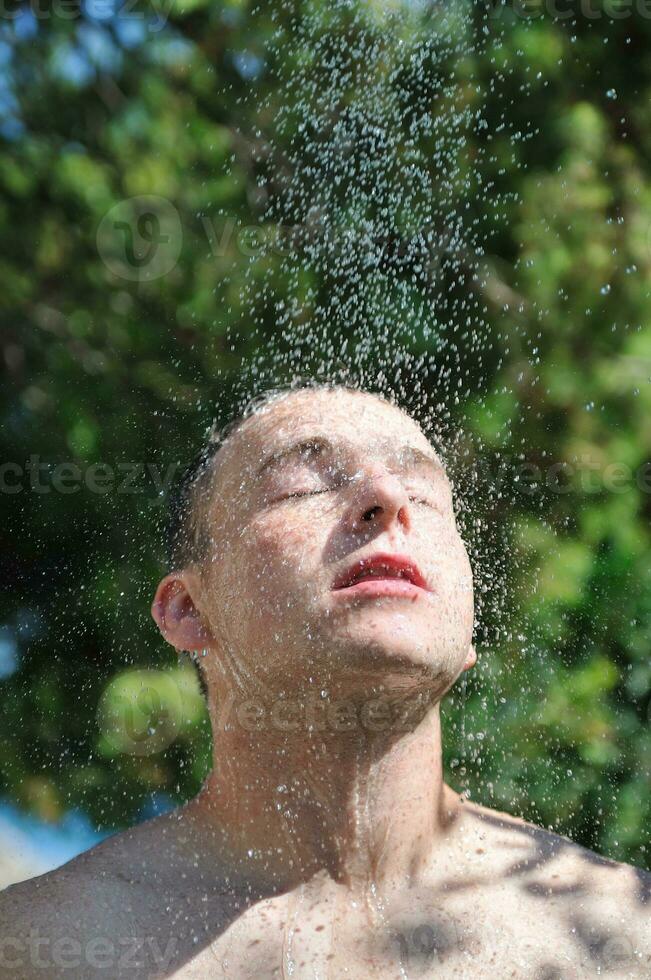 Mens wassen hoofd onder douche met vallend water foto