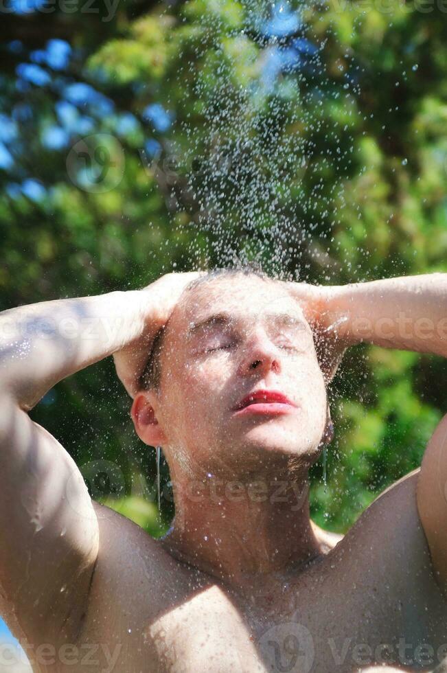 Mens wassen hoofd onder douche met vallend water foto