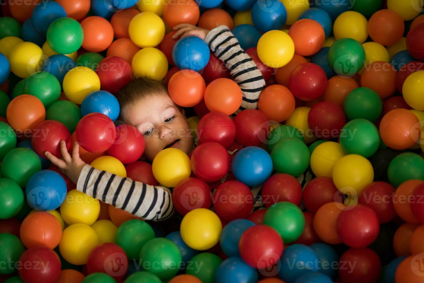 jongen hebben pret in honderden van kleurrijk plastic ballen foto