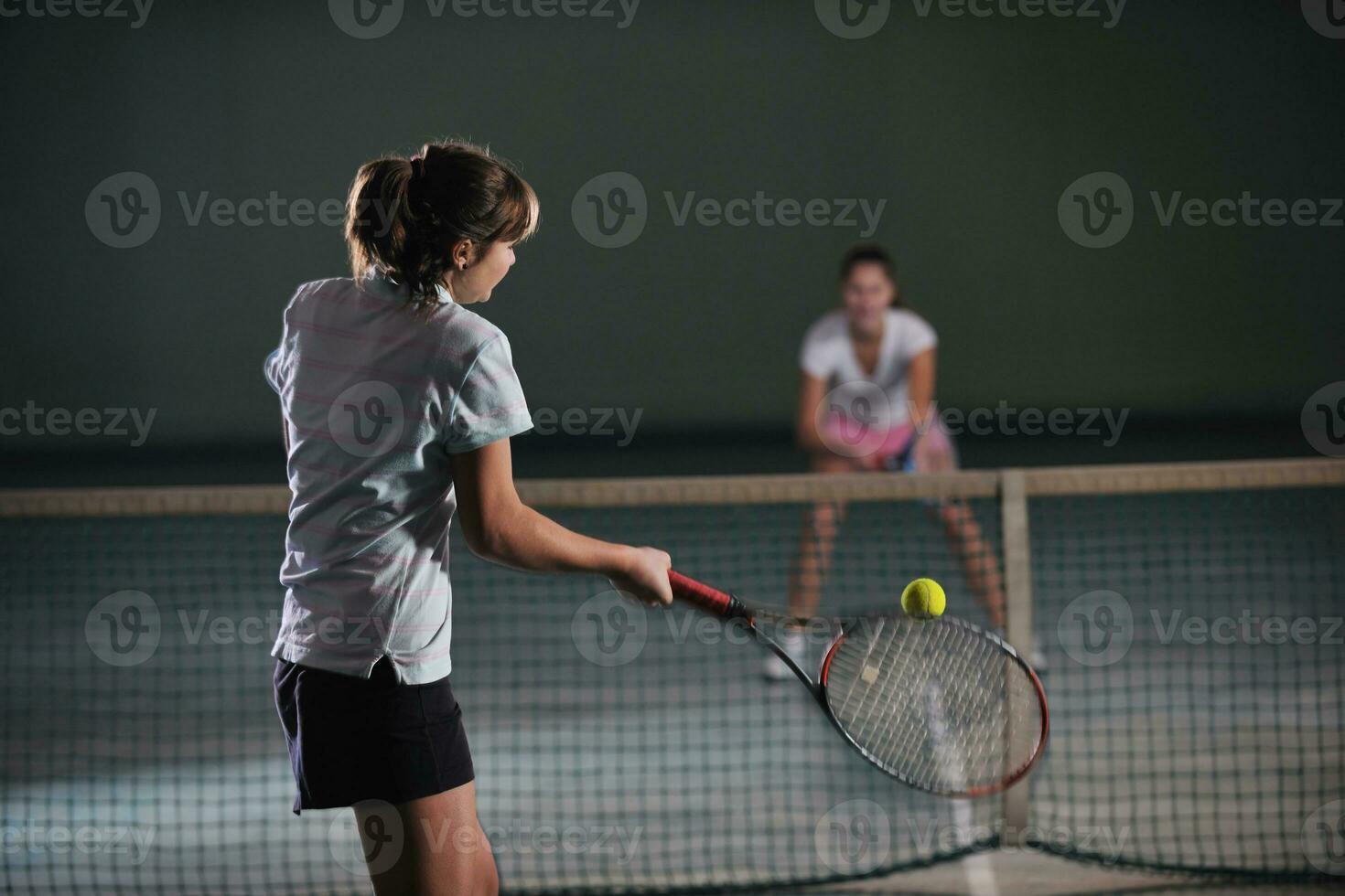 jong meisjes spelen tennis spel binnen- foto