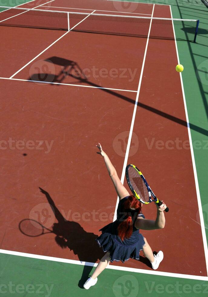 jonge vrouw speelt tennisspel buiten foto