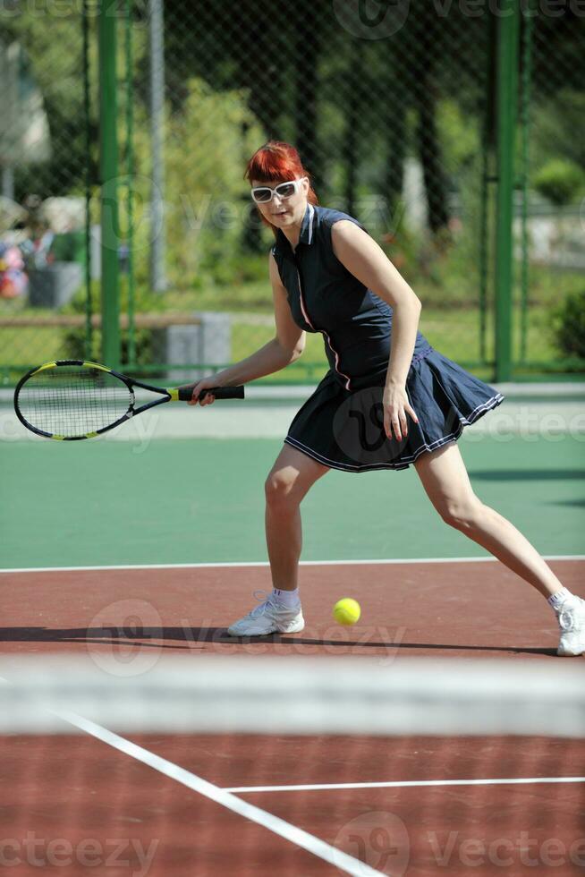 jonge vrouw speelt tennisspel buiten foto