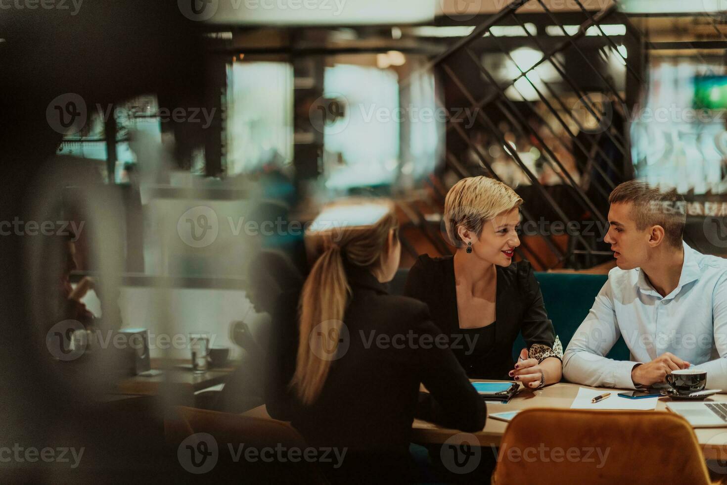 gelukkig mensen uit het bedrijfsleven glimlachen vrolijk gedurende een vergadering in een koffie winkel. groep van geslaagd bedrijf professionals werken net zo een team in een multicultureel werkplek. foto