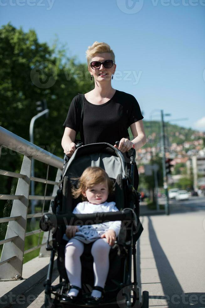 moeder geduwd haar baby dochter in een wandelwagen foto