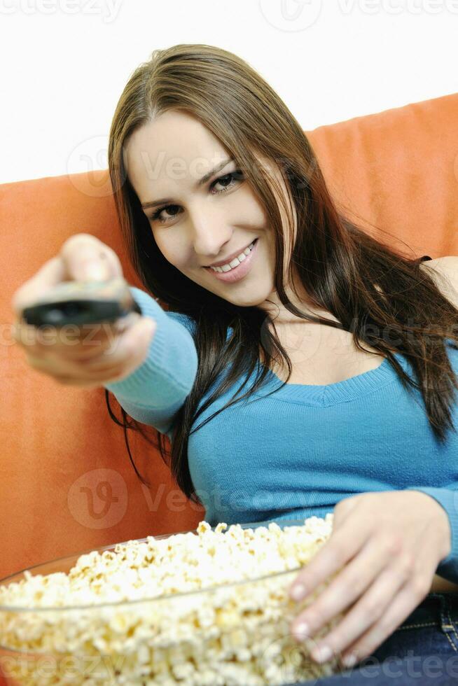 jong vrouw eten popcorn Aan oranje sofa foto
