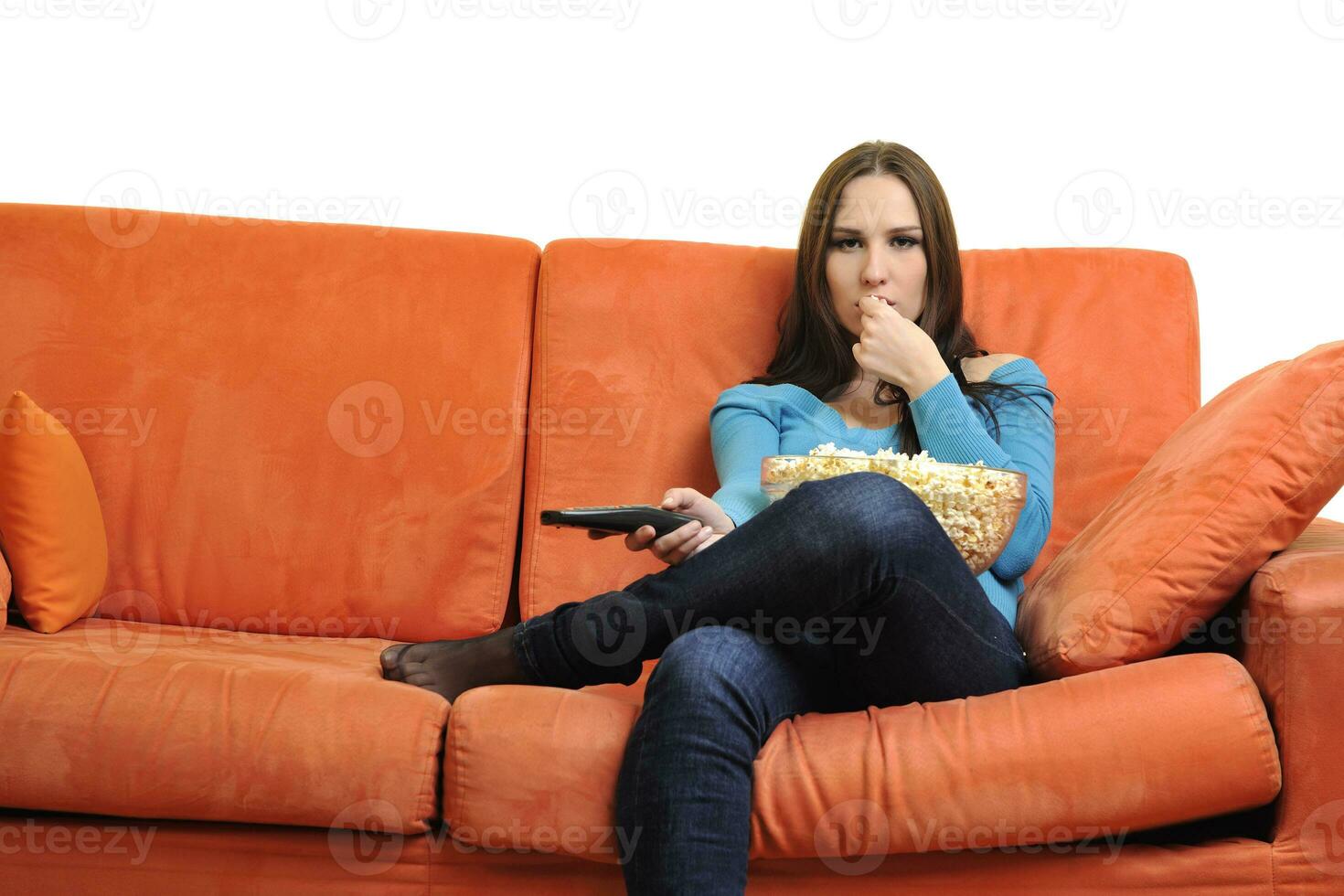 jong vrouw eten popcorn en aan het kijken TV foto