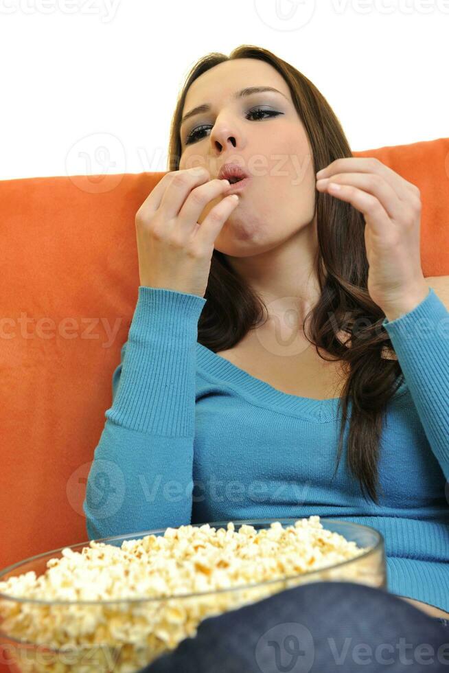 jong vrouw eten popcorn en aan het kijken TV foto