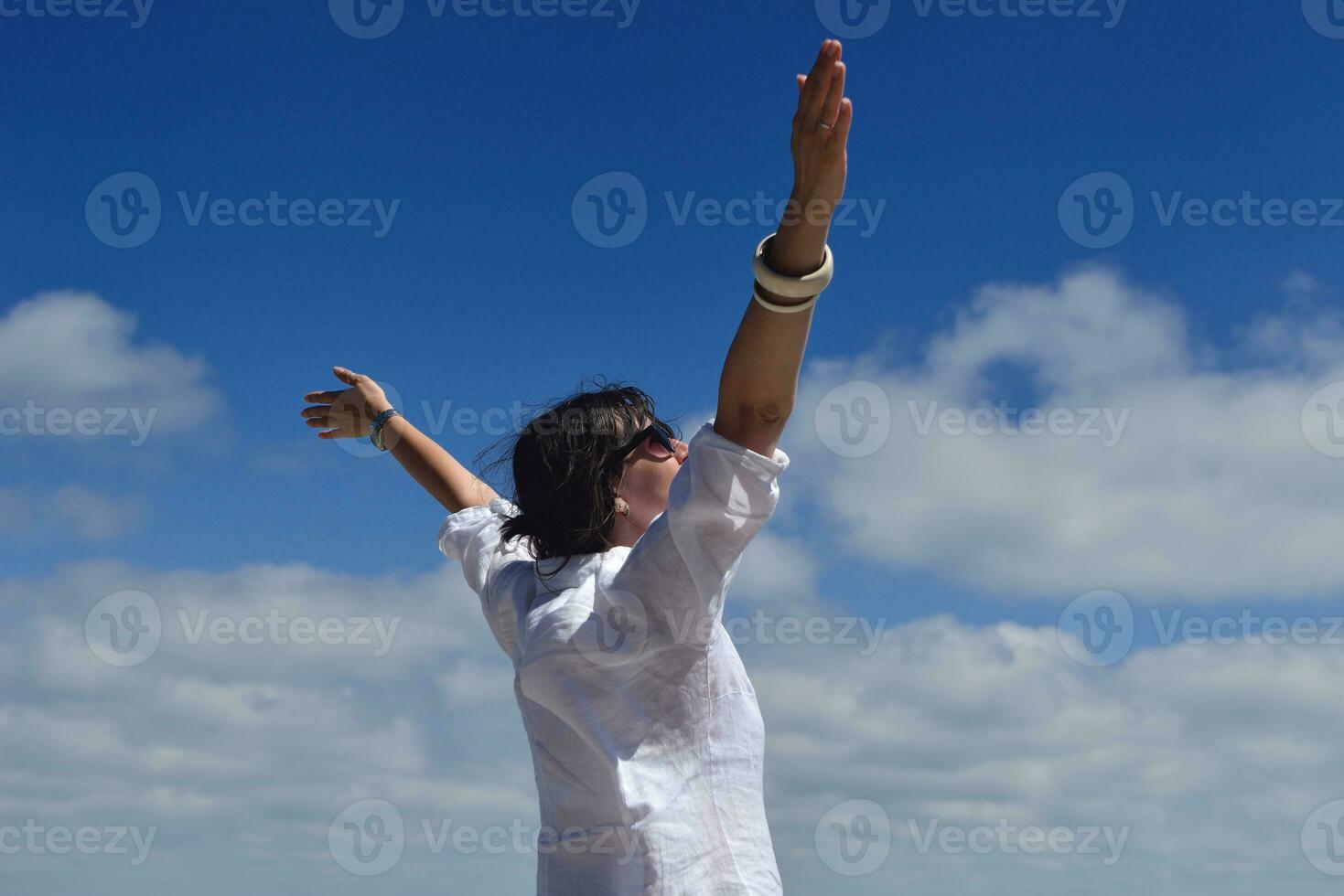 gelukkige jonge vrouw met spreidende armen naar de hemel foto