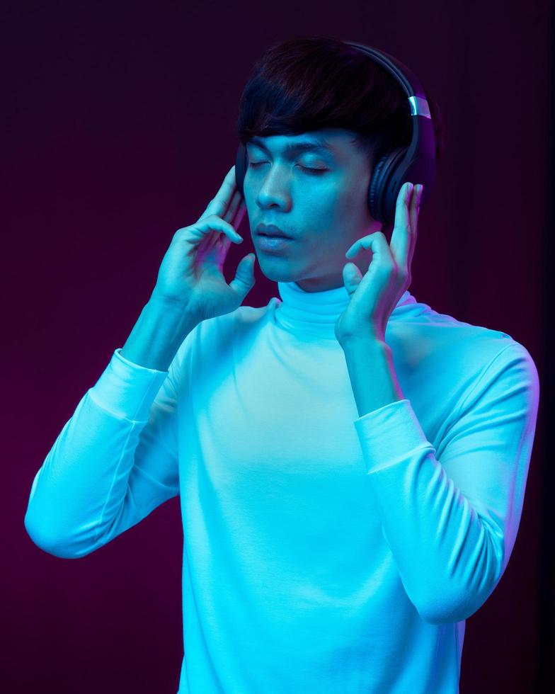 jonge aziatische man die muziek luistert met koptelefoon in neonlicht foto