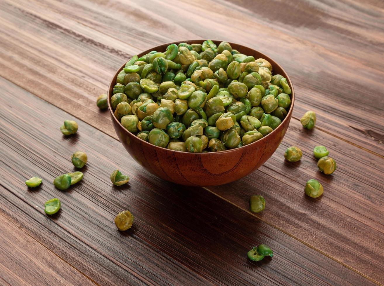 gezouten groene erwten in houten kom op tafel, gezonde snack foto