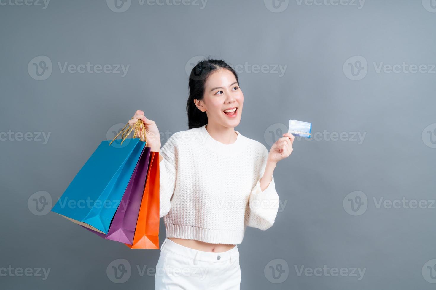 mooie aziatische vrouw met boodschappentassen en creditcard tonen foto