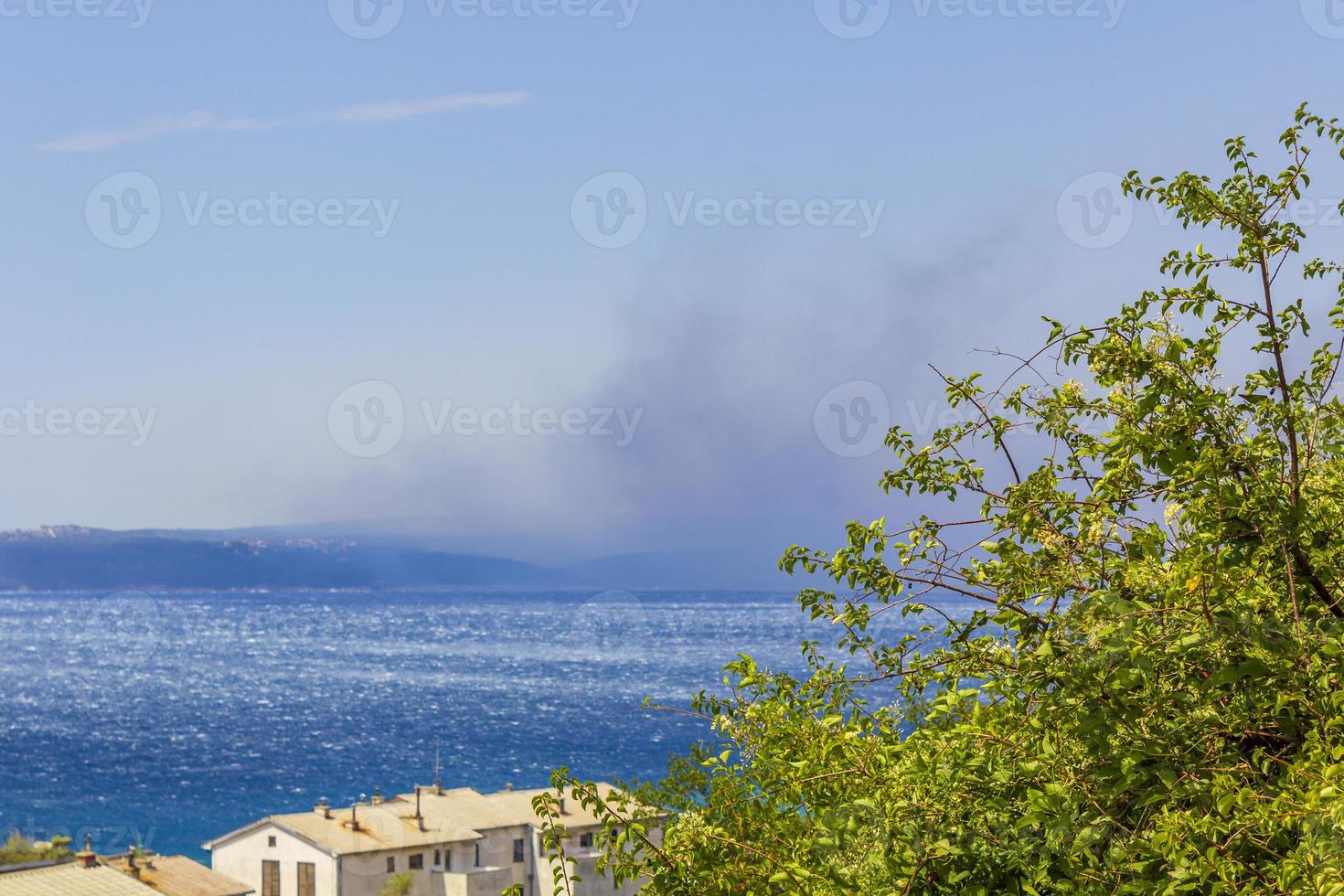 novi vinodolski in kroatië op een zonnige dag met rook van de bosbrand aan de horizon foto