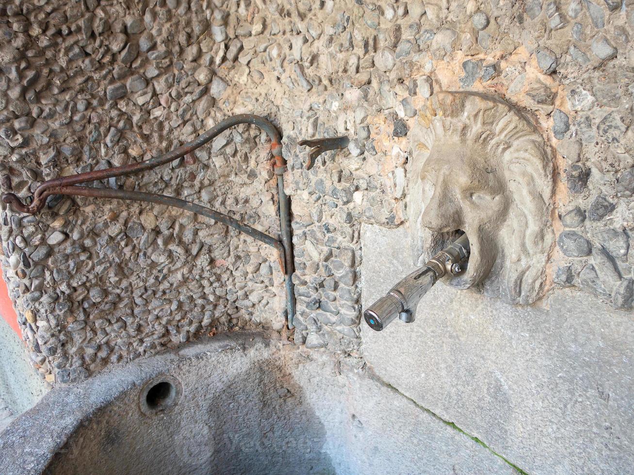 leeuwenkop in antieke stenen muur met moderne handwaskraan foto