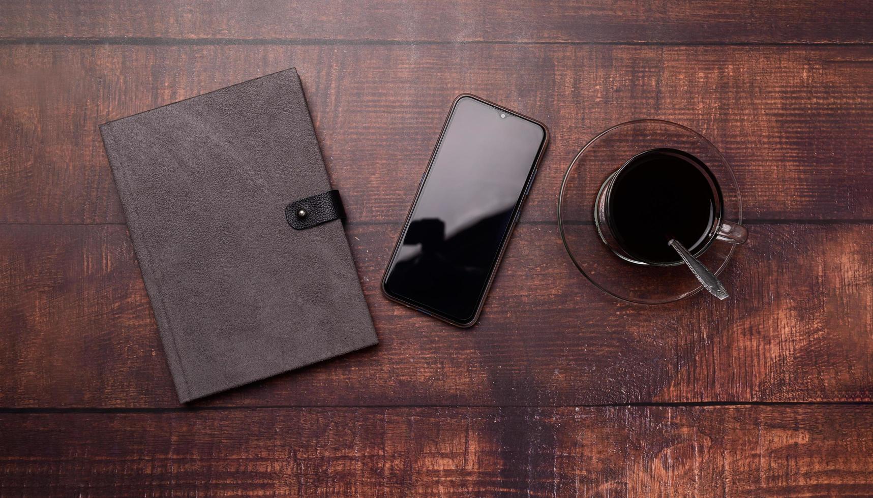 koffiemok, boek, smartphone op het bureau. foto