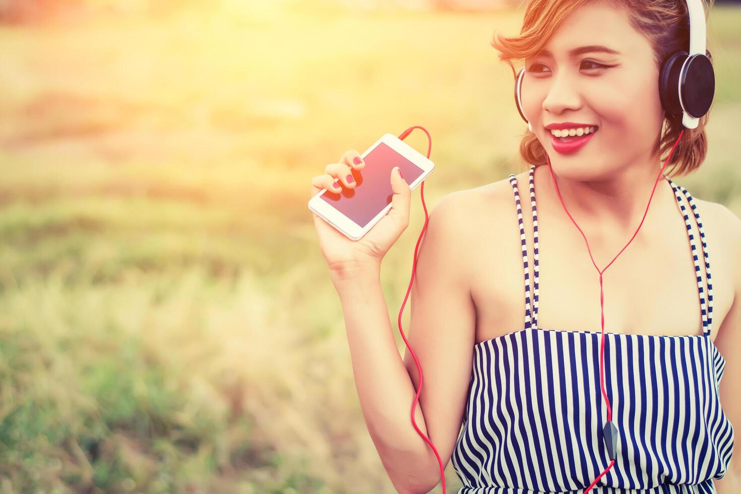 mooie sexy jonge vrouw die een hoofdtelefoon in het bloemenveld nadert foto