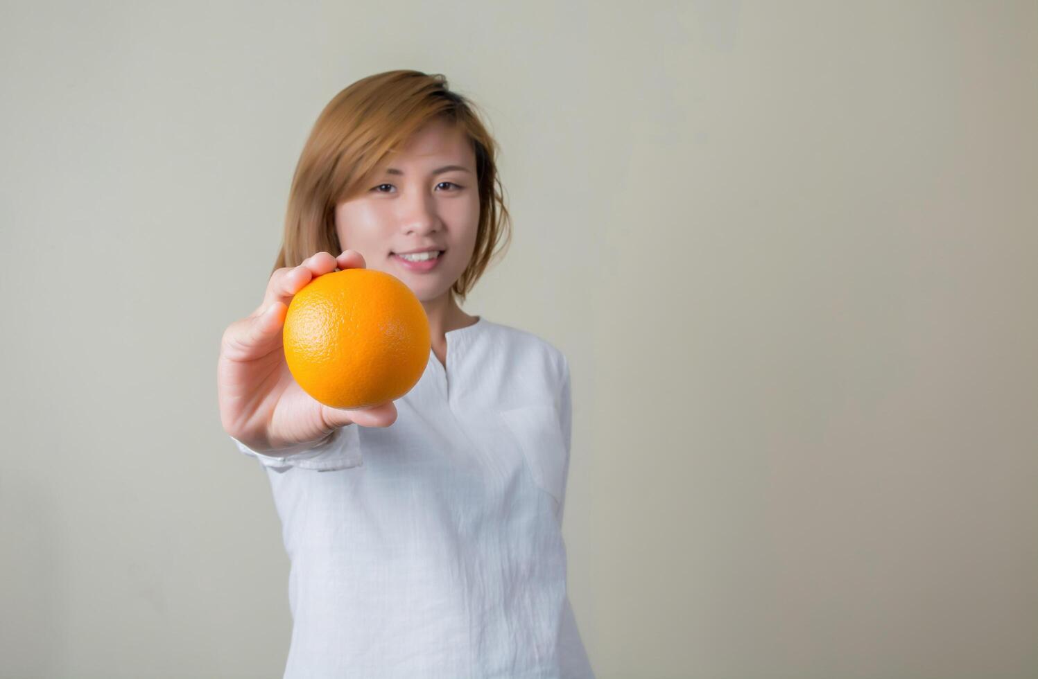 portret van mooie vrouwenglimlach die oranje fruit houdt foto