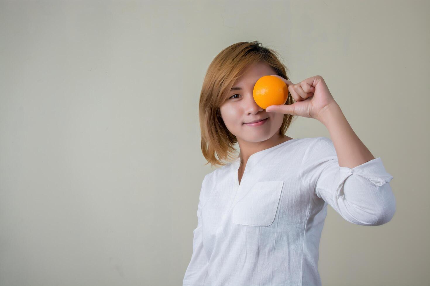 portret van mooie vrouwenglimlach die oranje fruit houdt foto