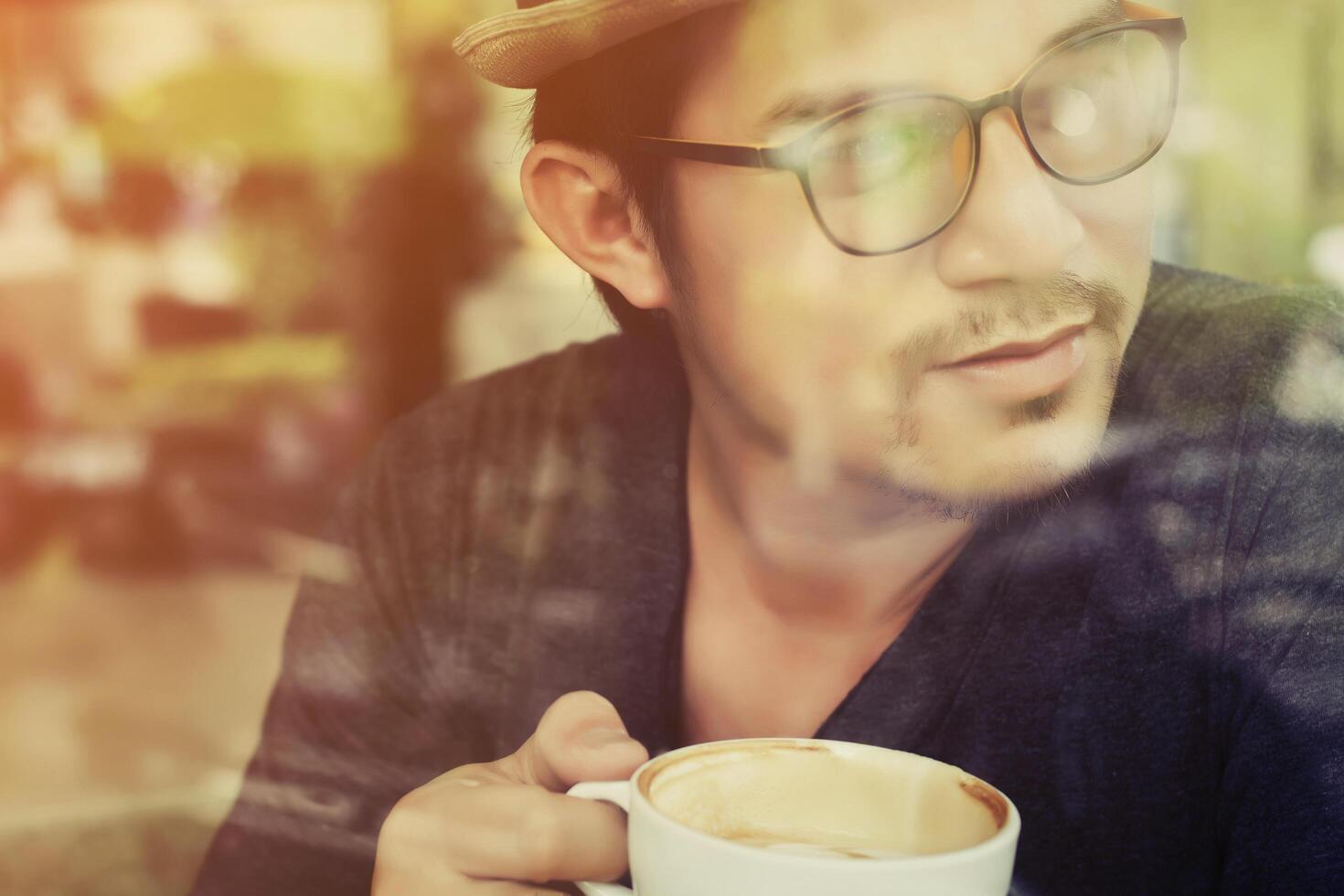 jonge man koffie drinken in café met zonsopgang foto