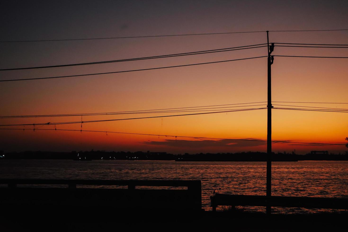 elektriciteitsmasten met draadkabel en straatlantaarnpaal bij zonsondergang. foto