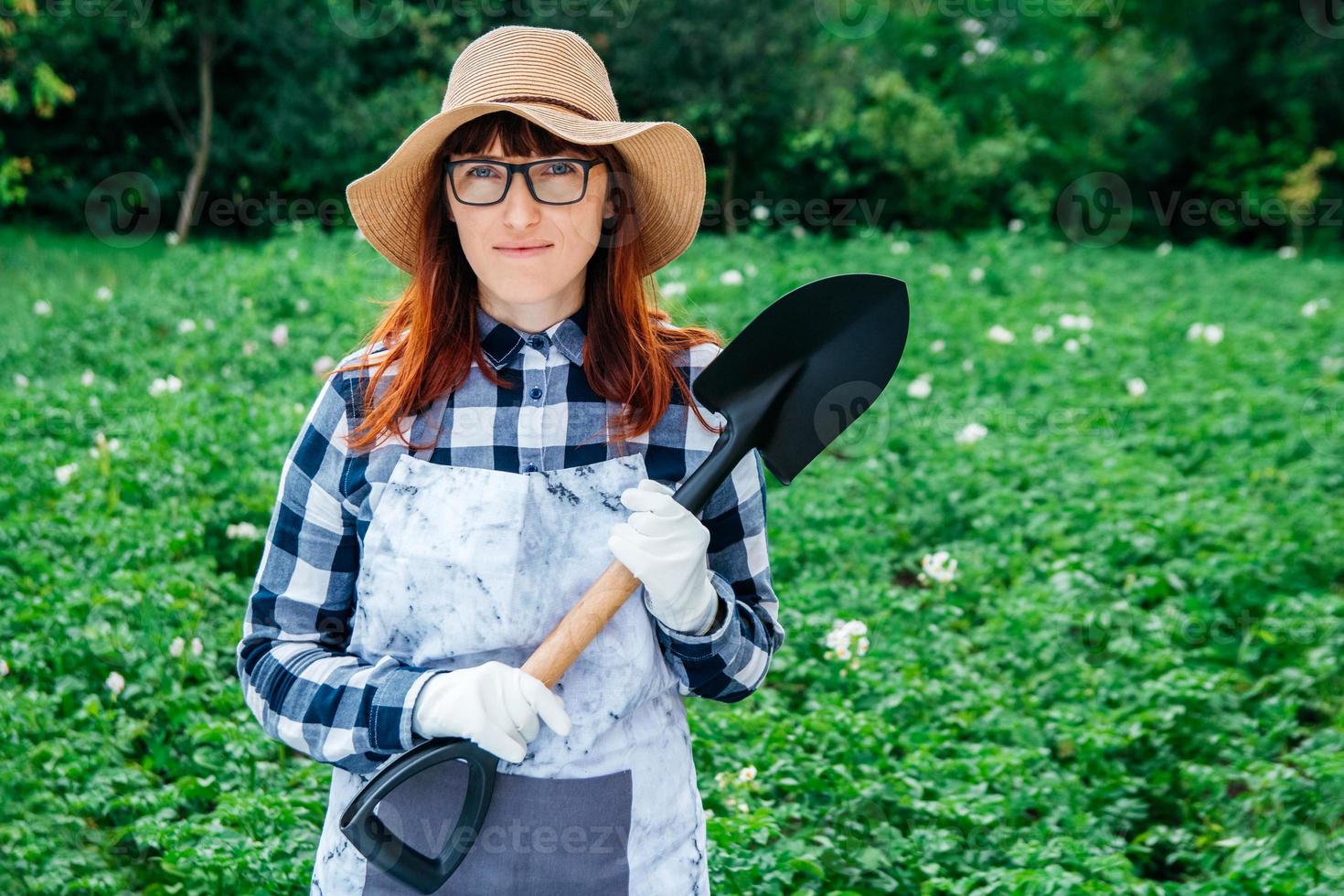 vrouw boer met een schop op een achtergrond van een groene tuin foto