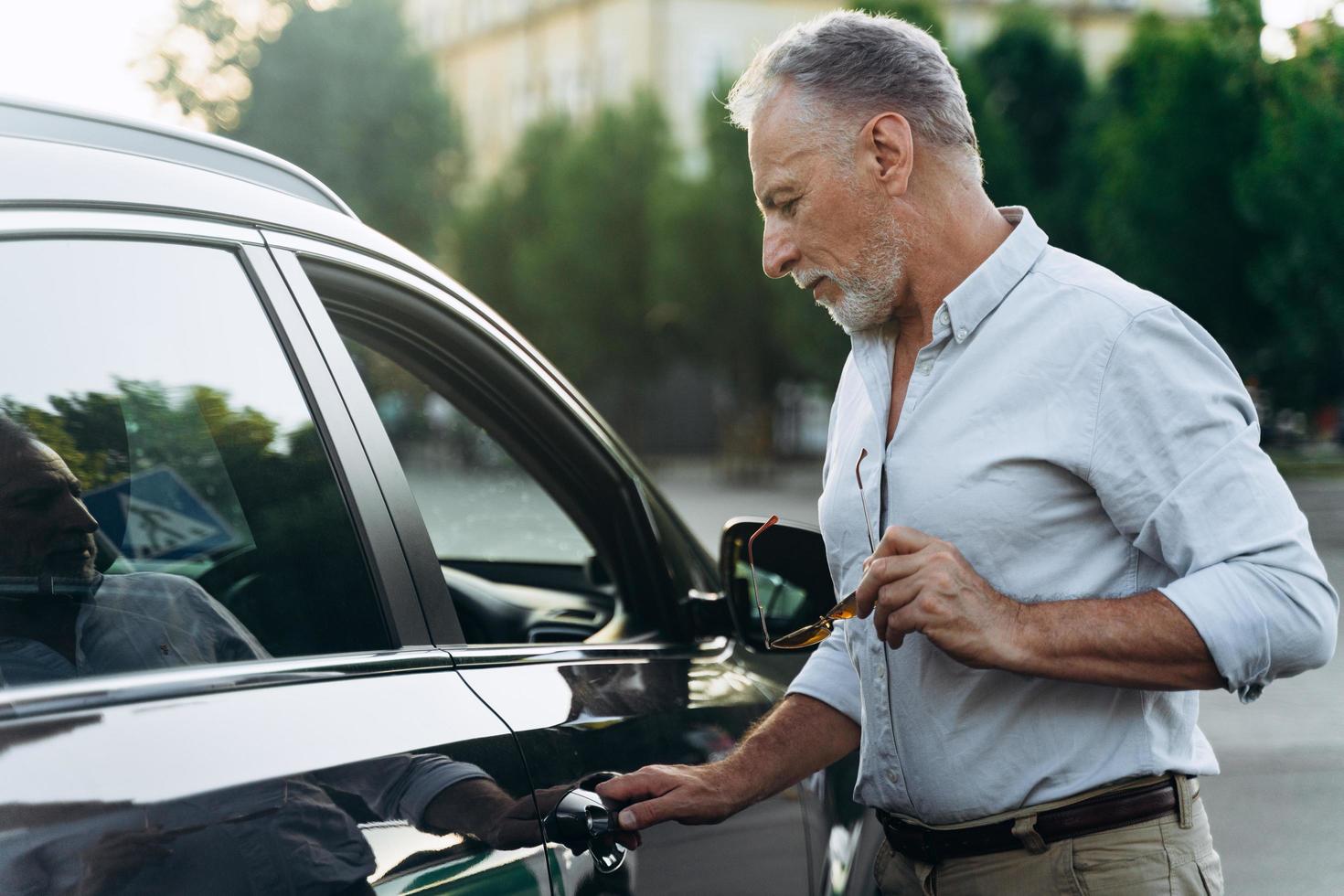 zakenman senior man stapt in zijn auto na een dag hard werken foto